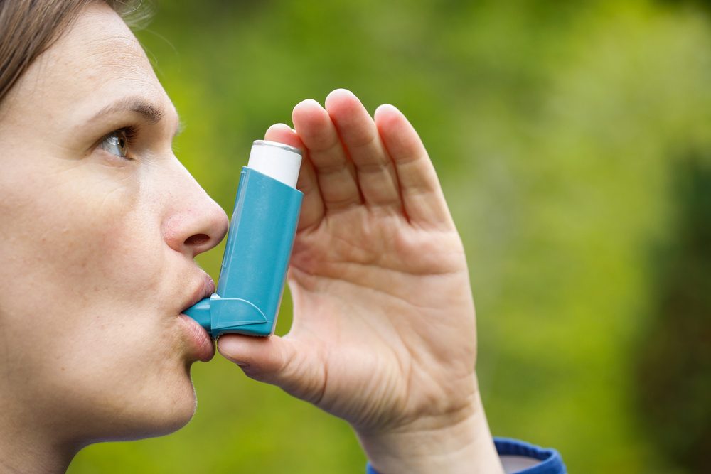 Asthma patient inhaling medication for treating shortness of breath and wheezing. Chronic disease control, allergy induced asthma remedy and chronic pulmonary disease concept.