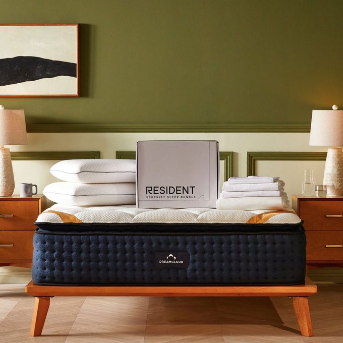 Mattress on wooden frame, with stacked pillows and a 