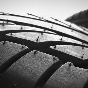 Tire tread shows detailed grooves and tiny rubber hairs, contrasted against a bright sky.