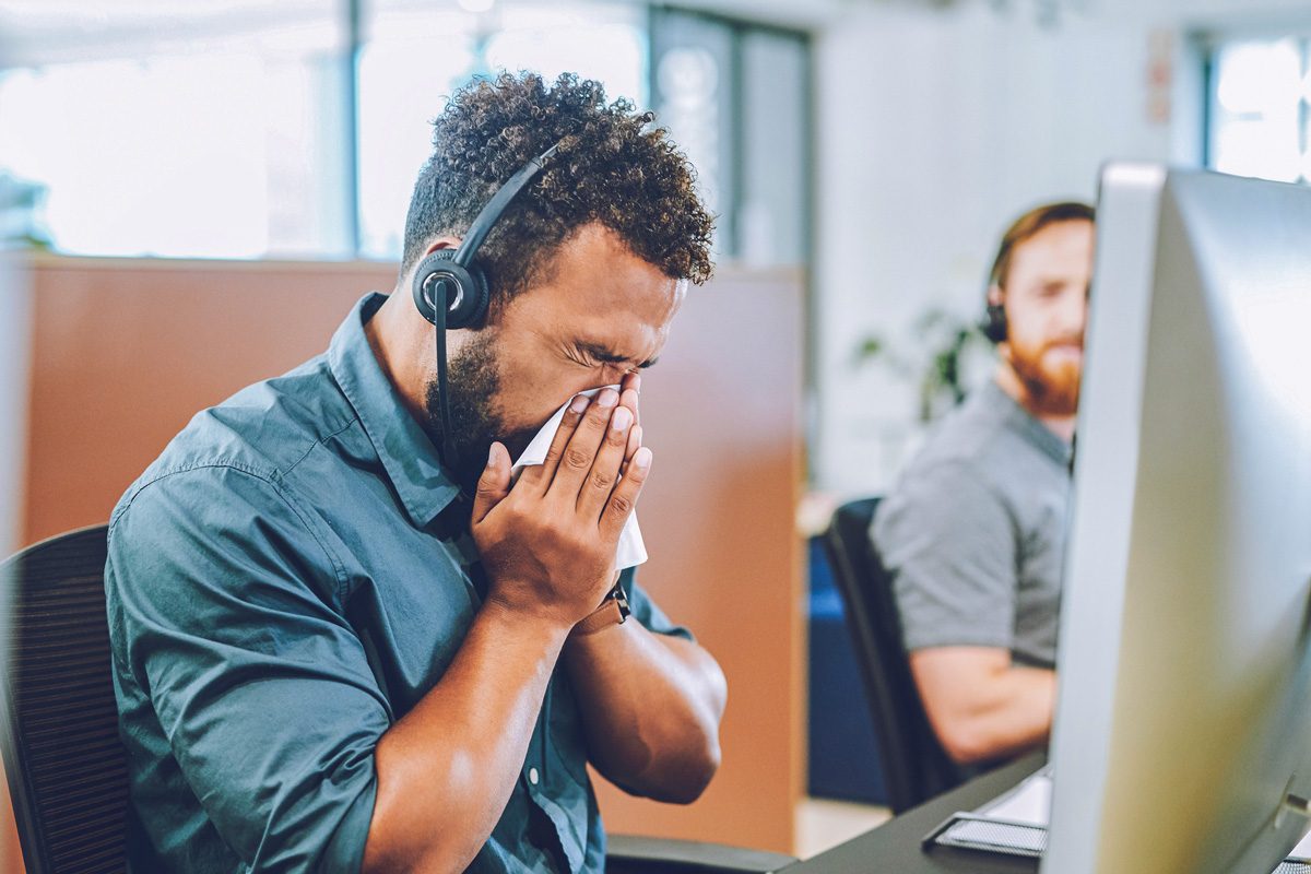 man sneezing in office