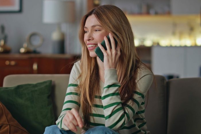 Smiling lady calling friends by smartphone at home close up. Happy woman talking